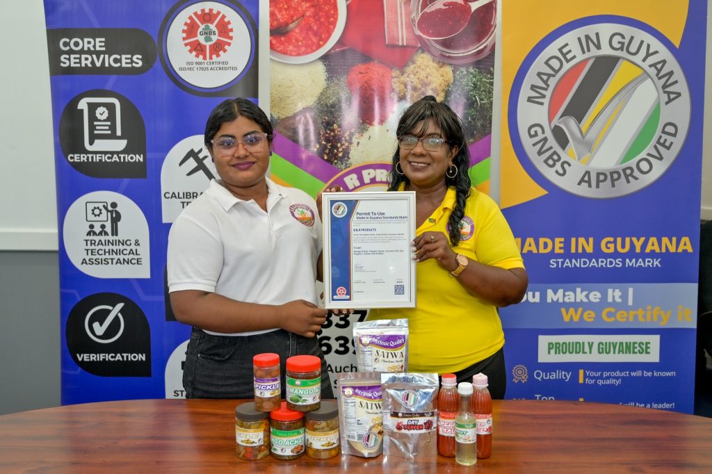 1.	Owner and CEO of B&R Products, Budwatty Ramnarine and her daughter Adelia Ramnarine proudly display GNBS Approved Made in Guyana Certificate alongside the certified products.